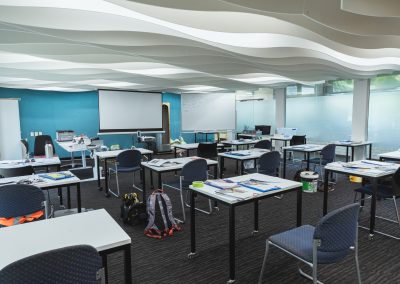 Modern classroom with individual desks, a smart board, and ample natural light from large windows.